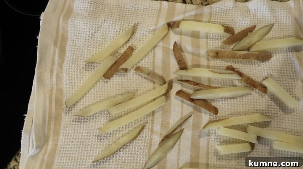Drained parboiled potato sticks laying on a dish towel to dry off