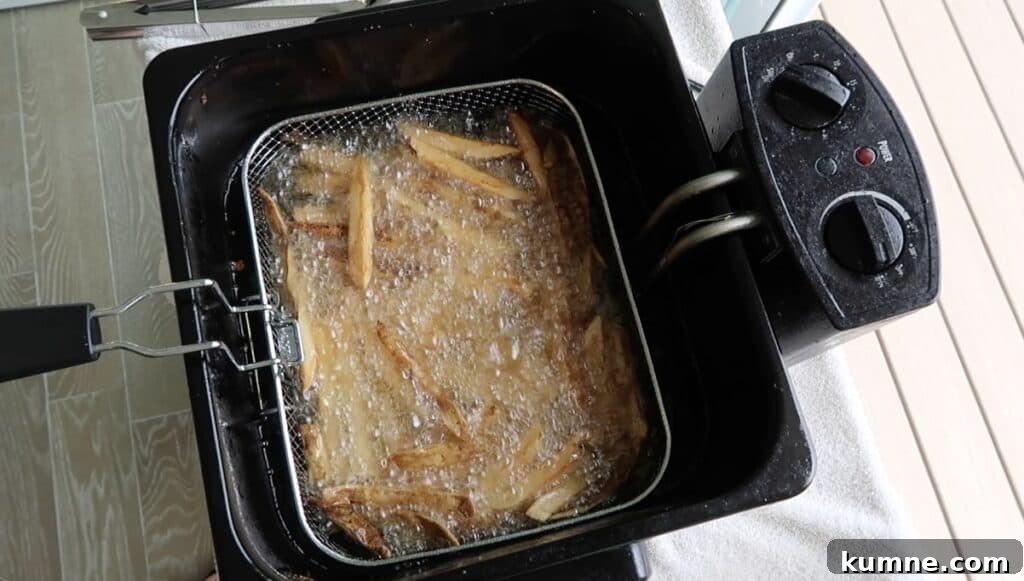 French fries in basket being lowered back into the oil for a double fry.