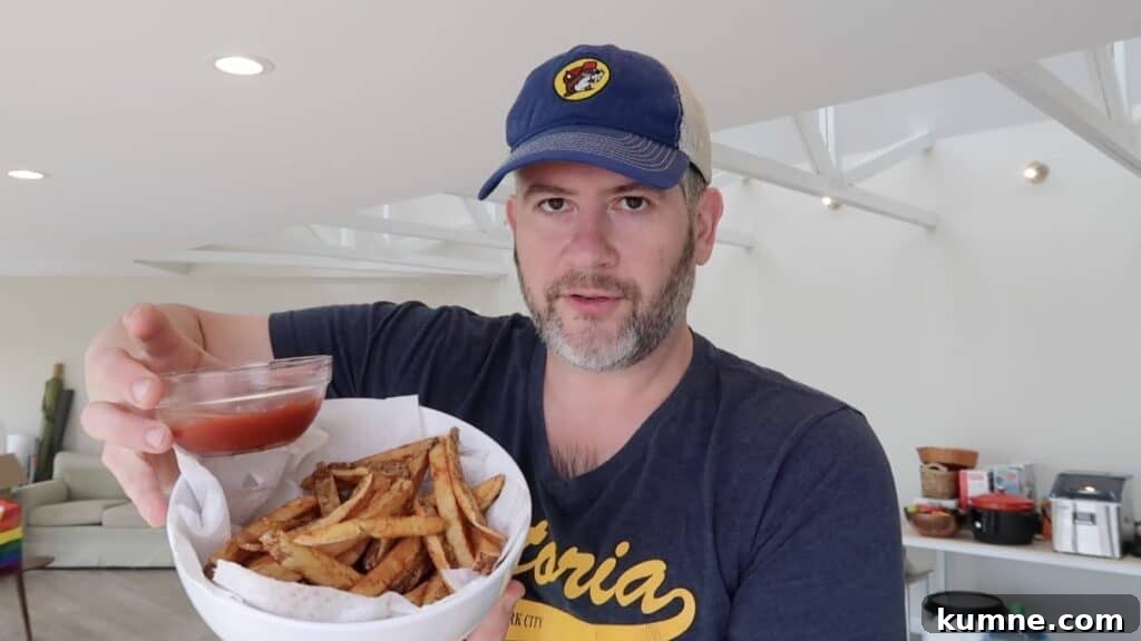 Man holding bowl of French fries with ketchup