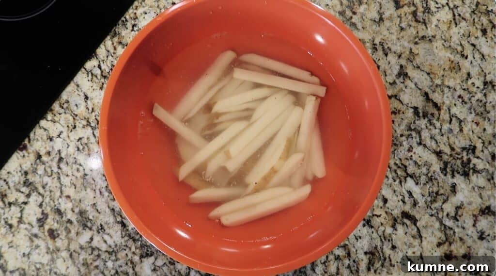 Cold water covering potato sticks in bowl