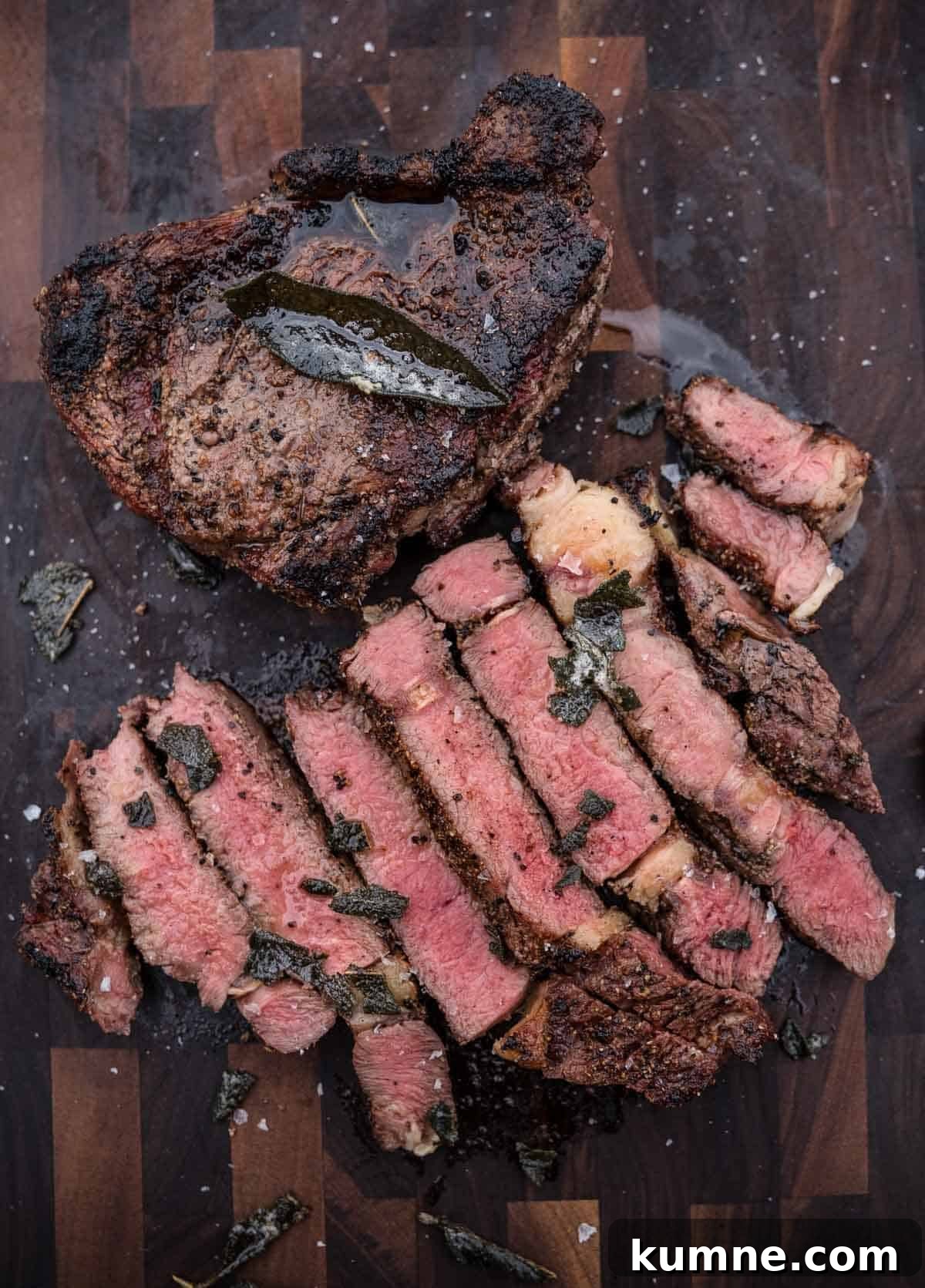 Two grilled bison steaks on a cutting board, one whole and one cut into slices.