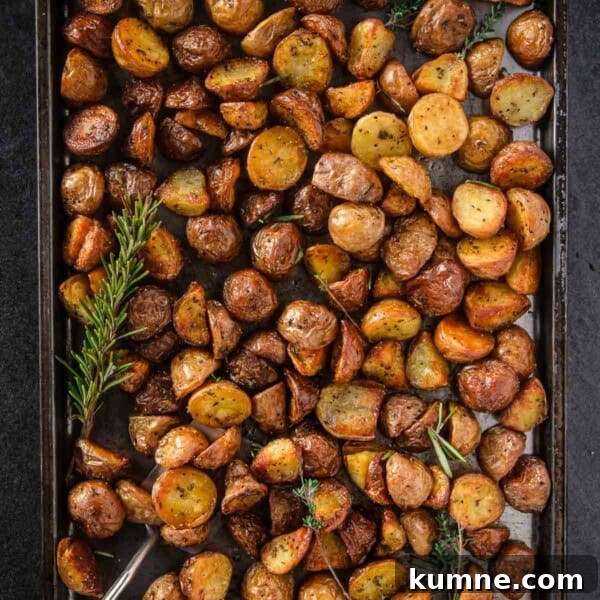 Perfect Roasted Potatoes on a sheetpan with a sprig of rosemary