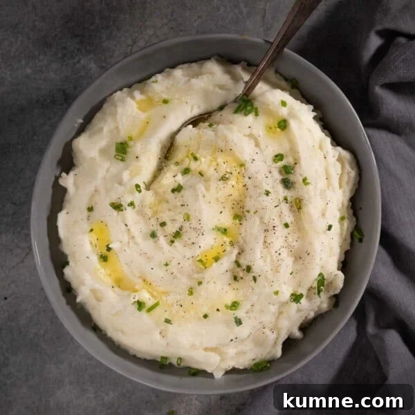 Horseradish mashed potatoes in a bowl with melted butter and chives.