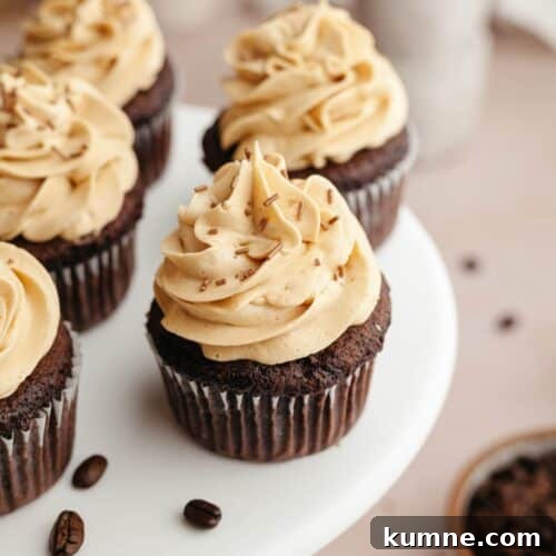 Chocolate cupcakes with coffee frosting on a white cake stand.