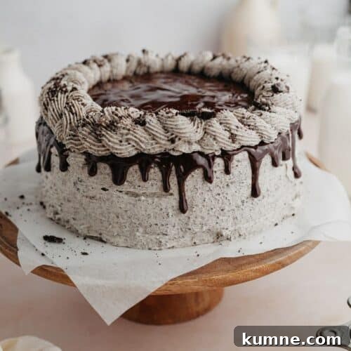 An oreo drip cake on a wooden cake stand