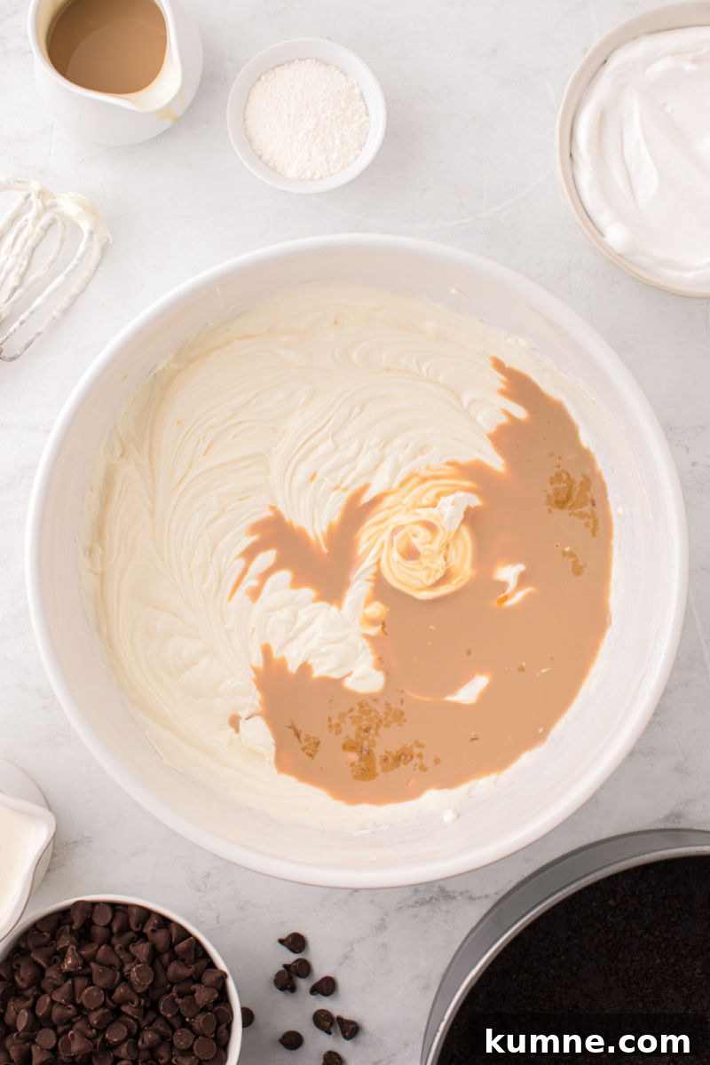 baileys cheesecake filling base in a mixing bowl with irish cream poured in