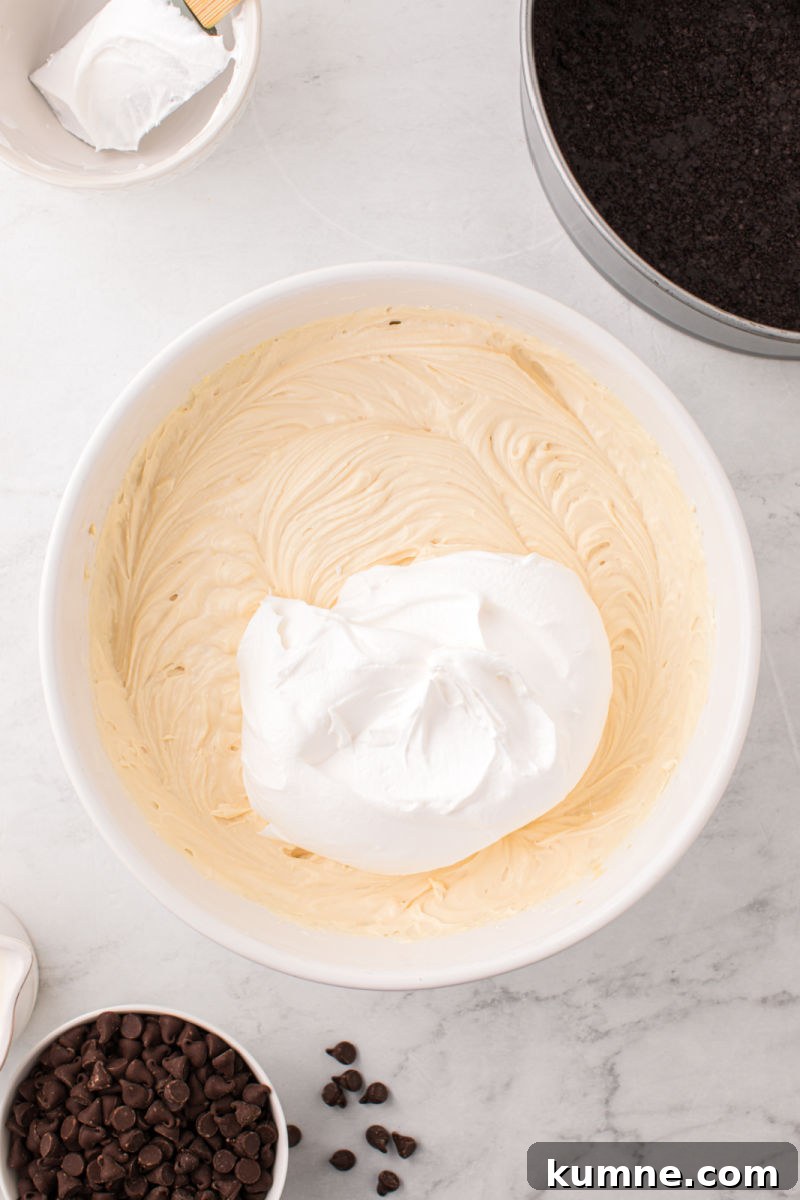 cool whip added to a bowl with baileys cheesecake filling