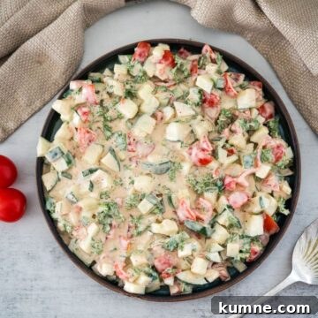 A plate of diced vegetable salad with a creamy dressing on a table.