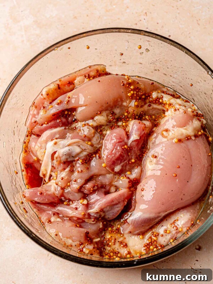 Honey Mustard Grilled Chicken Recipe for Juicy, Flavorful Results 5 Raw chicken thighs marinating in a honey mustard garlic mixture.