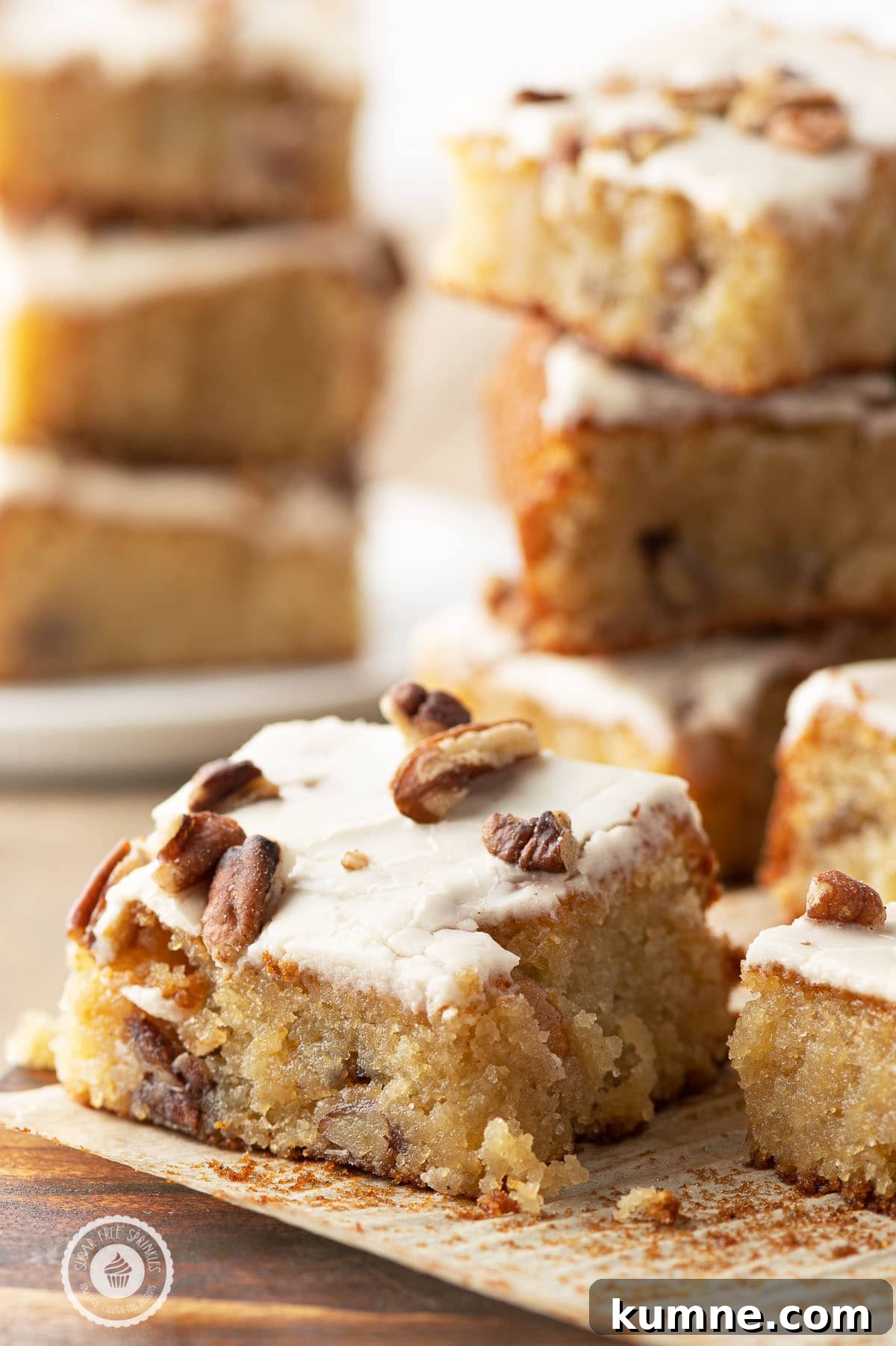 Low-Carb Maple Pecan Blondies — Chewy, Gooey Treats 5 A gooey glazed pecan blondie fresh out of the oven on a parchment paper on top of a rustic wooden cutting board