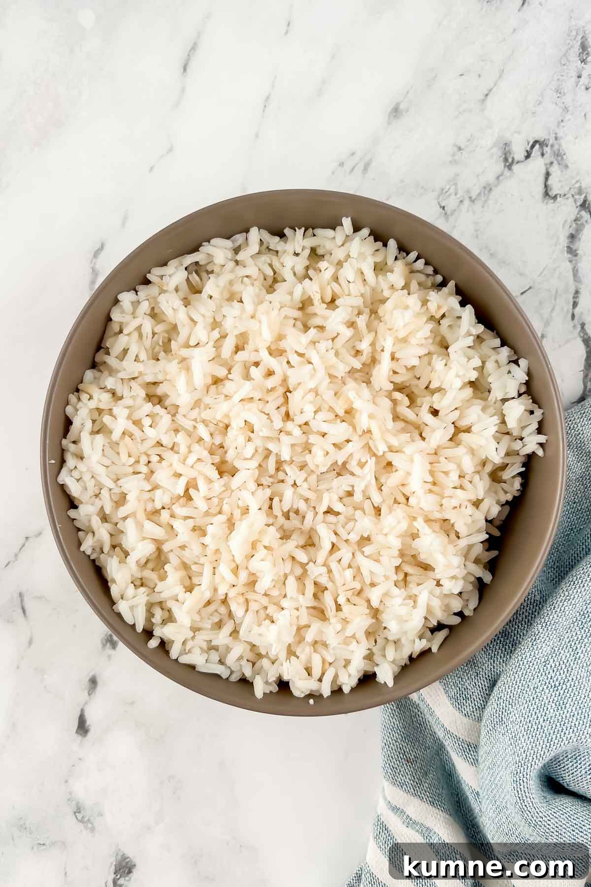 Festive Mexican-Style Fiesta Rice Recipe 4 White rice in tan bowl on marble background.