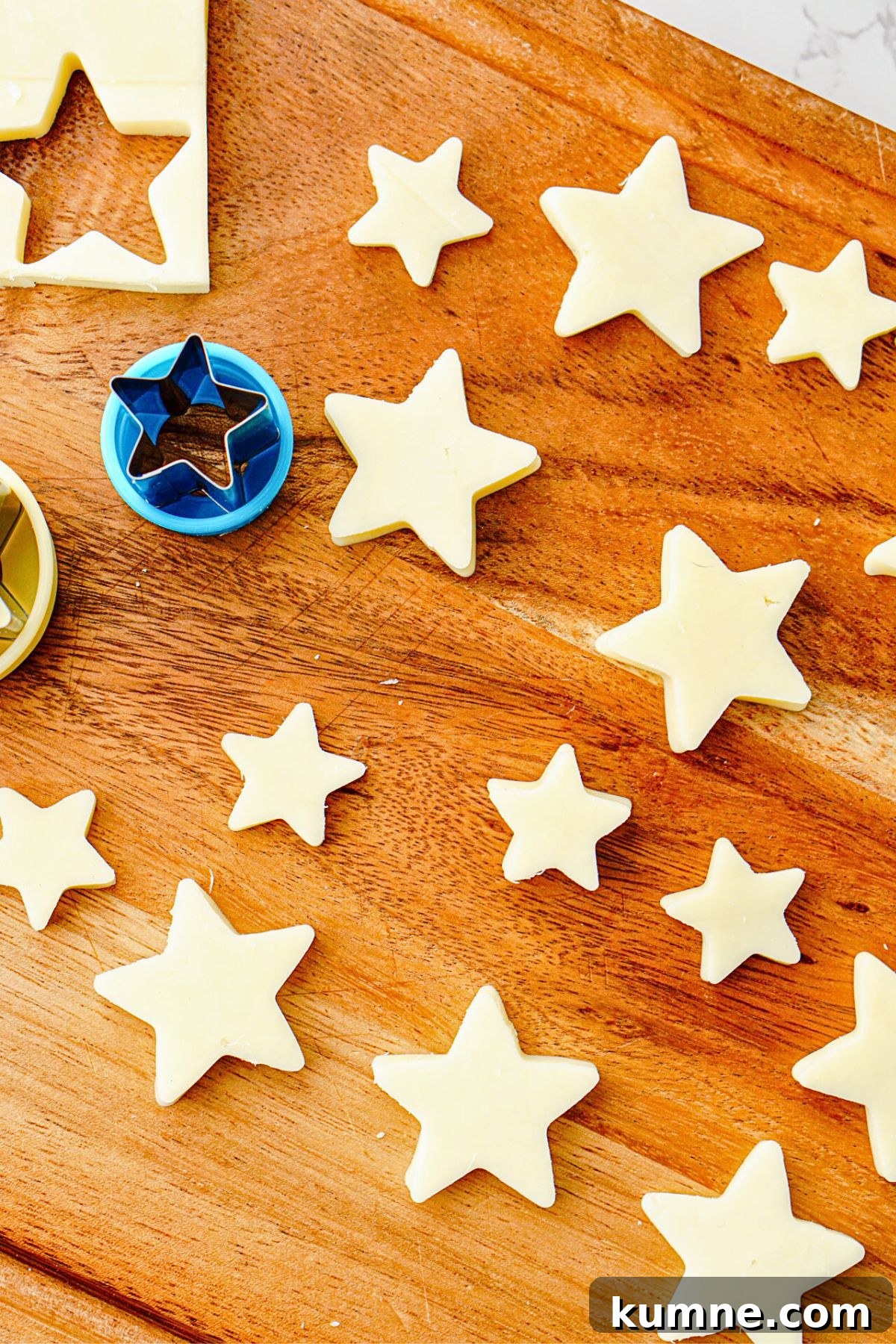 Berry Caprese Salad with Balsamic Glaze and Fresh Basil 6 Mozzarella cheese cut into star shapes on a wooden cutting board.