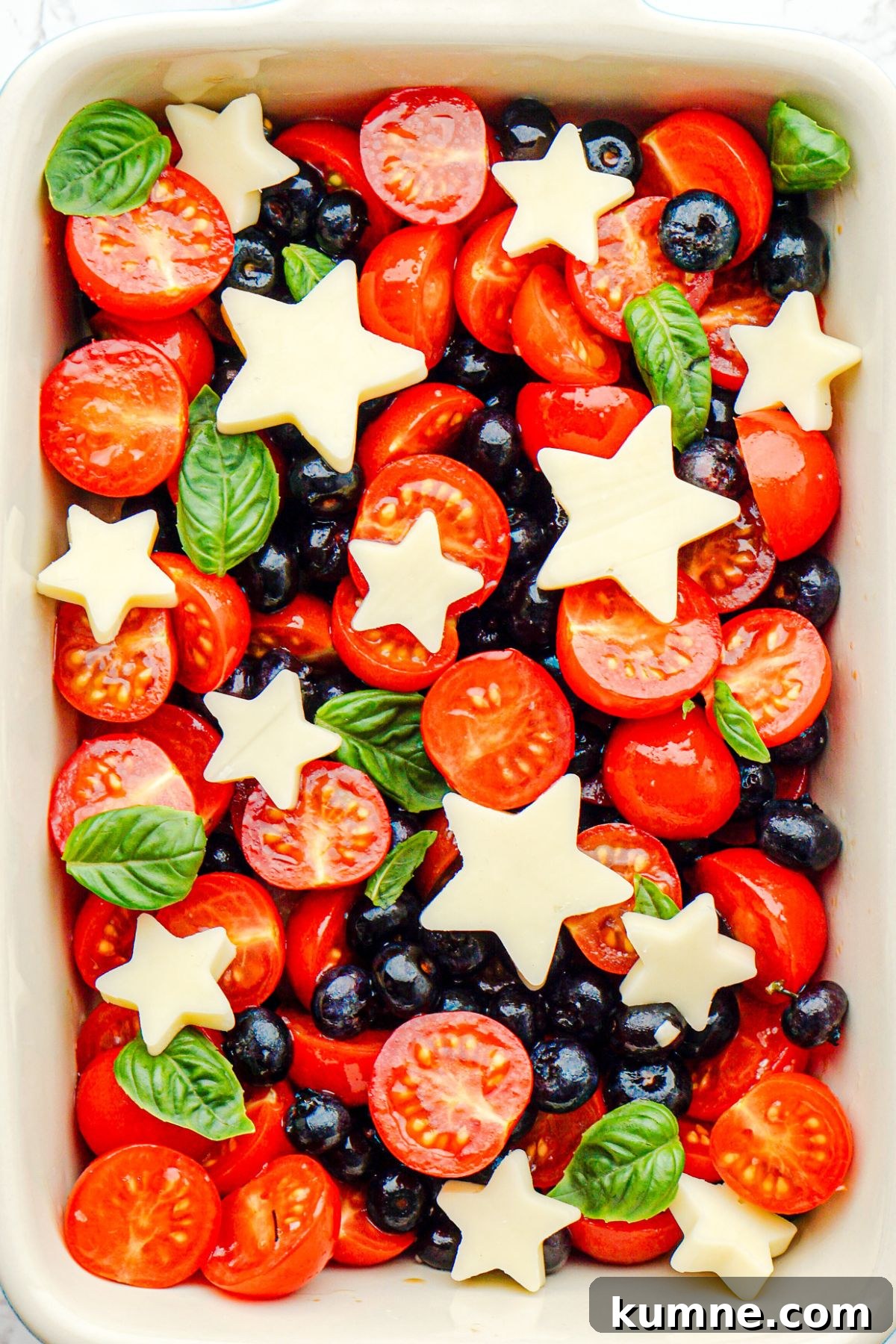 Berry Caprese Salad with Balsamic Glaze and Fresh Basil 7 Blueberries, tomatoes, and mozzarella cheese shaped into stars, in a rectangle baking dish.