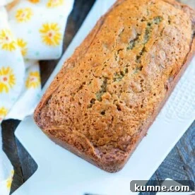 Ultimate Moist Zucchini Bread Recipe for Perfect Loaves Every Time 5 A loaf of moist zucchini bread sits on a white cutting board, accompanied by a yellow floral napkin, reminiscent of a delightful zucchini bread recipe.