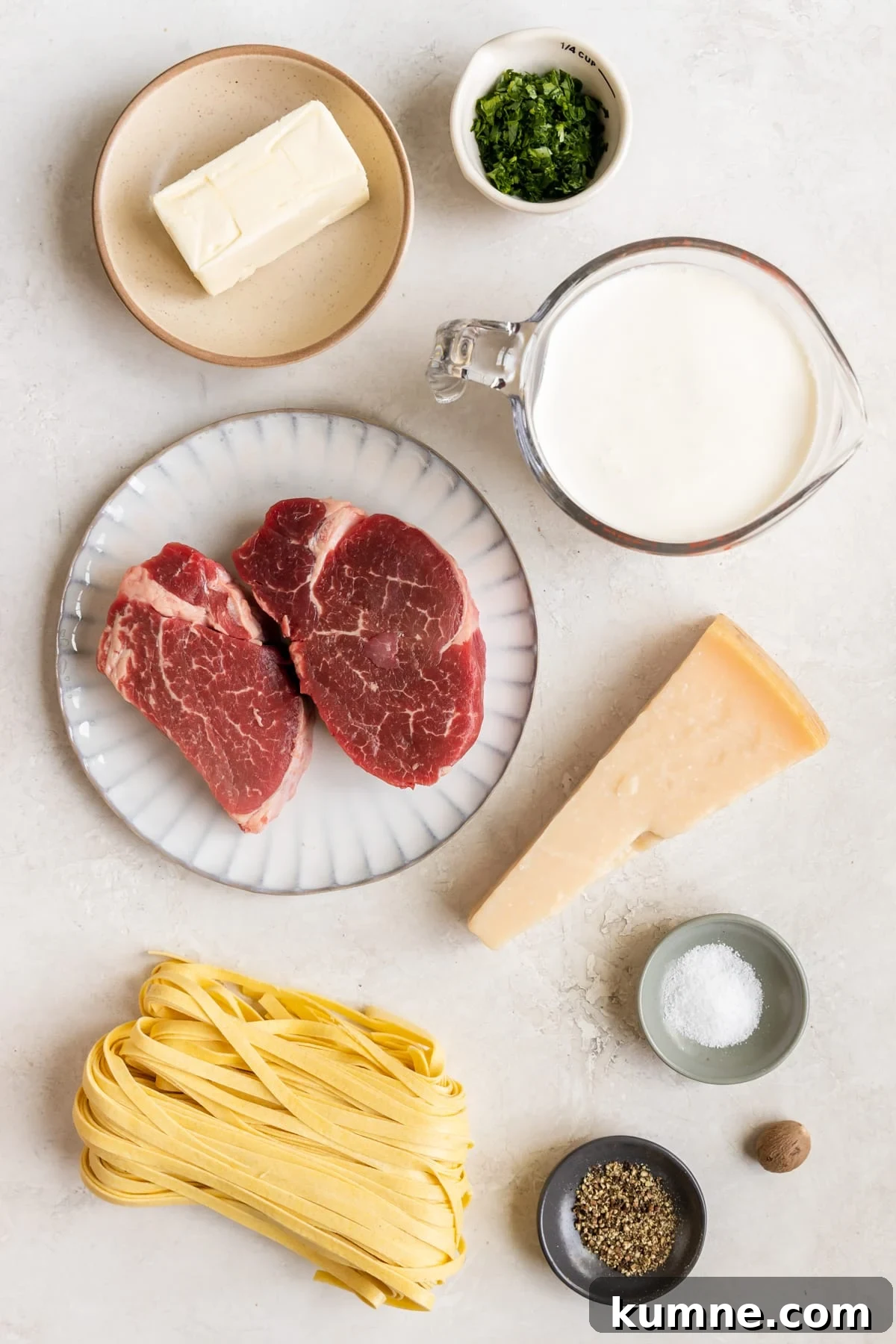 ingredients to make steak Alfredo on plates and in small bowls and measuring cups.