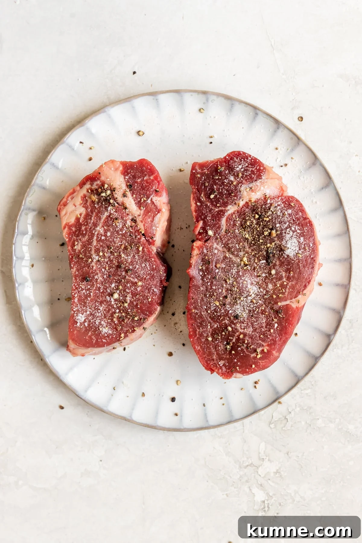 steak on a plate seasoned with salt and pepper.