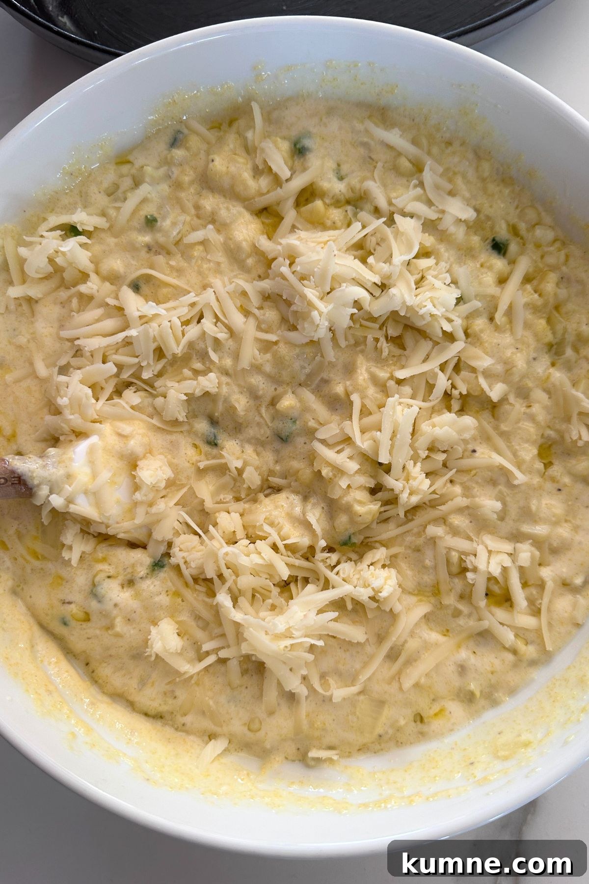Creamy Baked Jalapeño Cheddar Corn Pudding Recipe from Scratch 6 Sautéed corn mixture and shredded cheese, being stirred together.