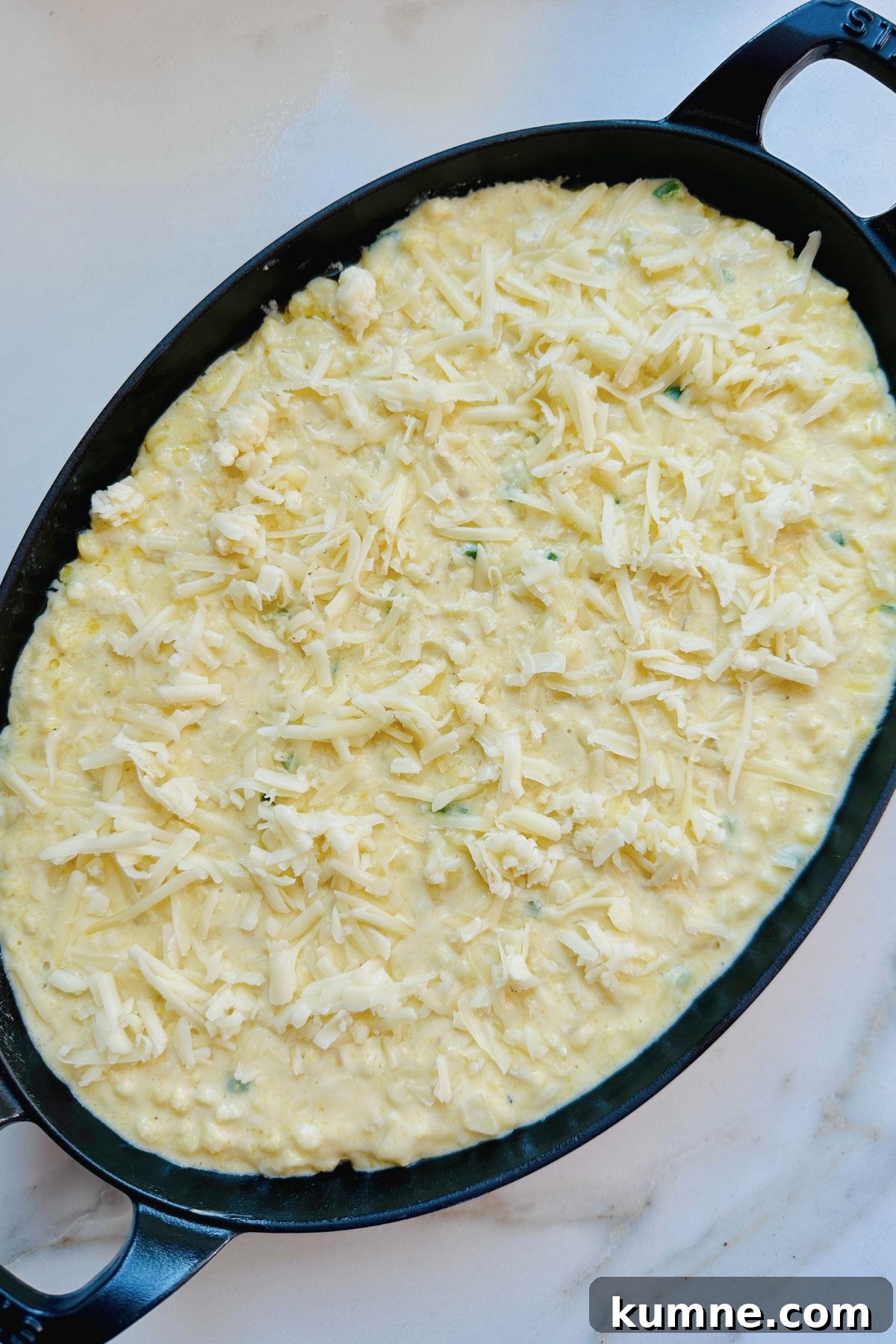 Creamy Baked Jalapeño Cheddar Corn Pudding Recipe from Scratch 7 Batter poured into prepared baking dish sprinkled with extra cheese on top.