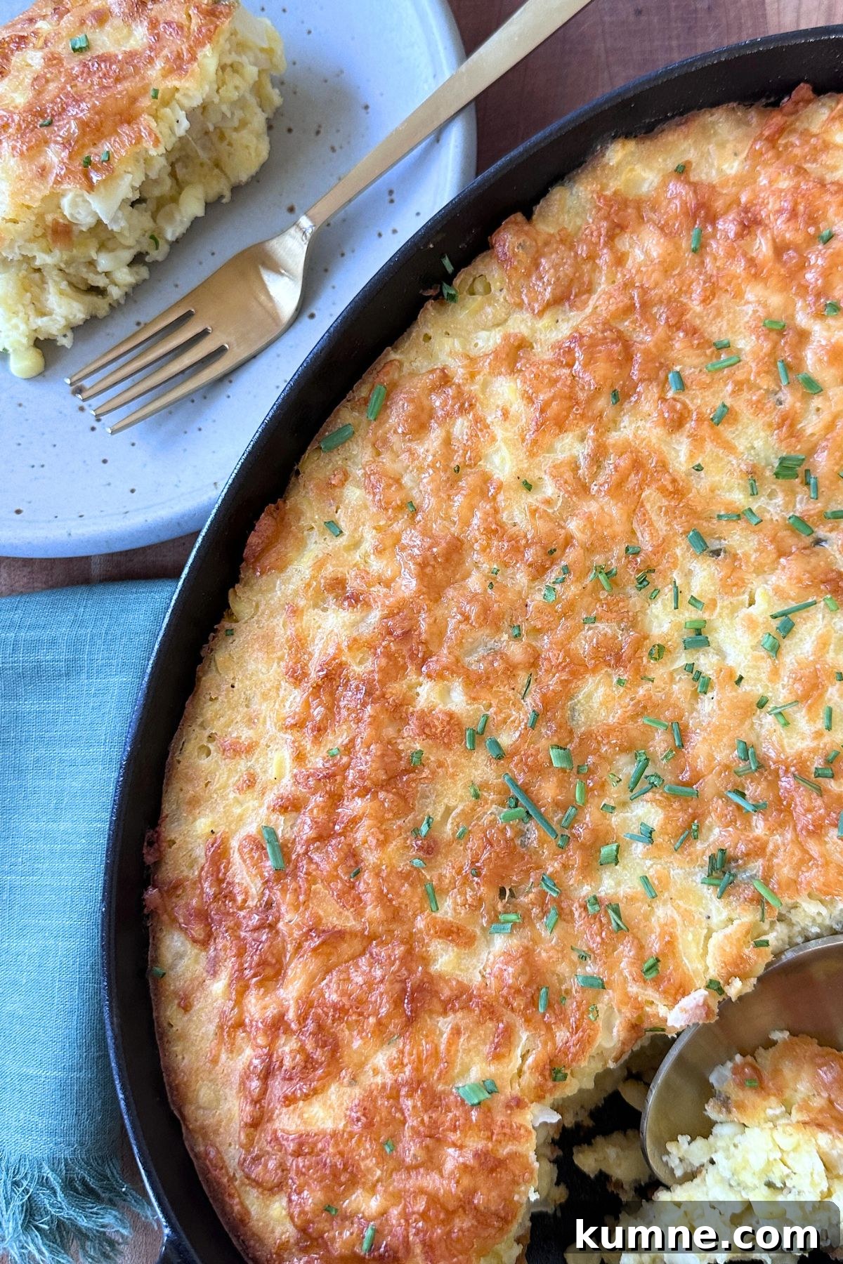 Creamy Baked Jalapeño Cheddar Corn Pudding Recipe from Scratch 10 Close-up of golden corn pudding baked in a black dish with corner slices cut out, served with a plated portion beside it and a fork ready to eat.