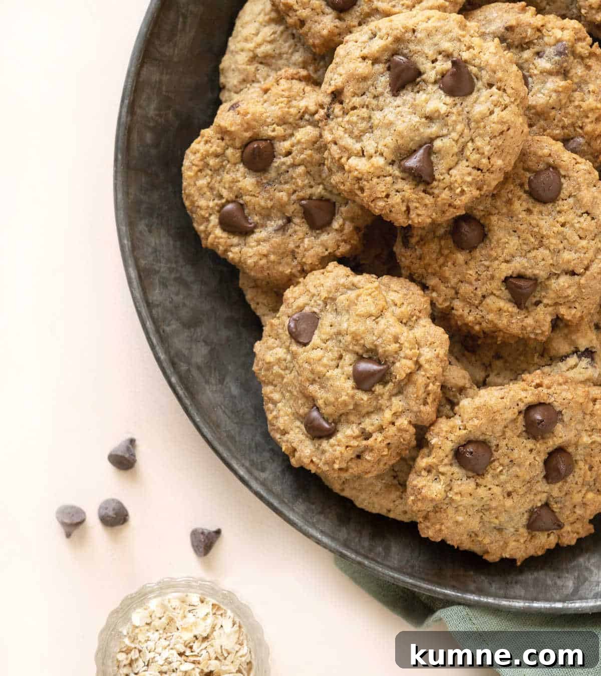 Chewy Chocolate Chip Oatmeal Cookies Recipe for Homemade Treats 7 A metal plate with chocolate chip oatmeal cookies in a pile. Light peach surface.