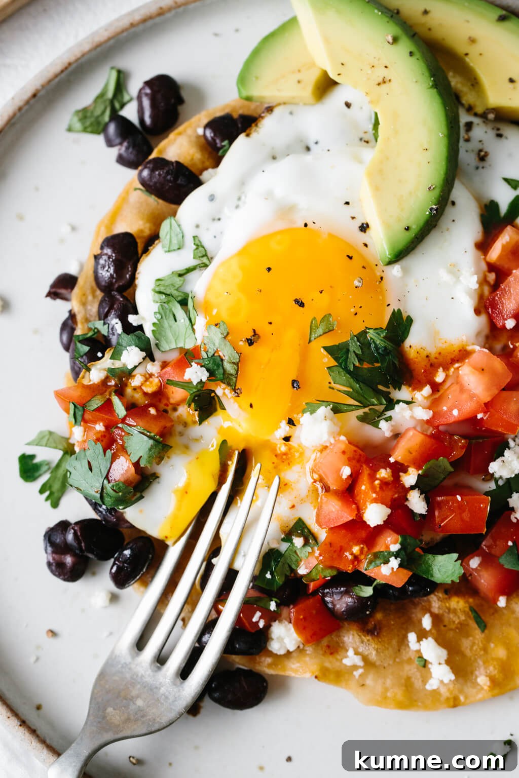 A fork broke open the yolk on a plate of huevos rancheros.