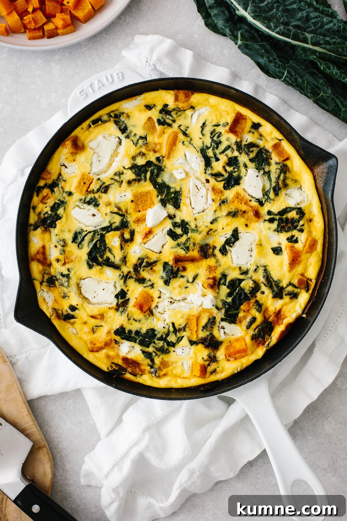 Butternut squash frittata in a white saute pan on a table.