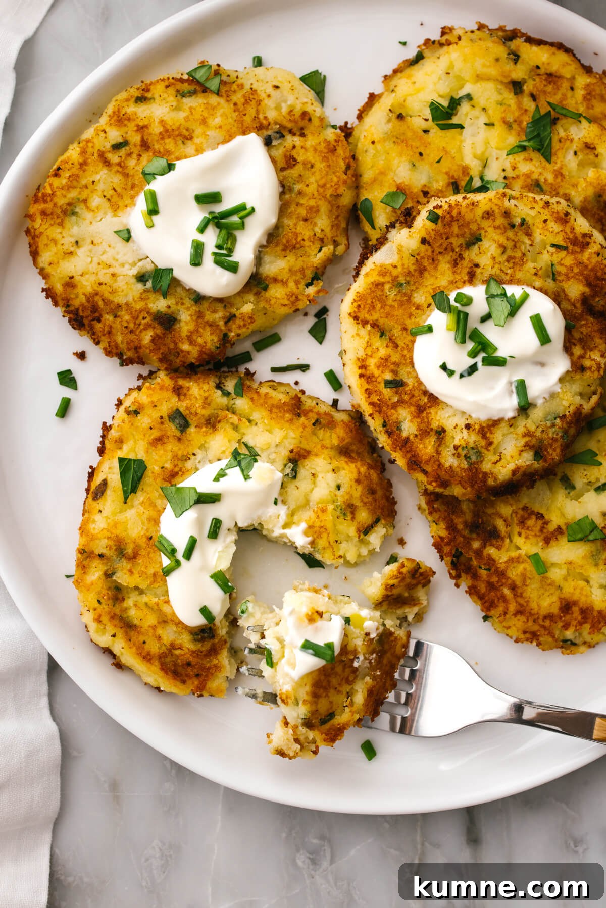A plate of potato pancakes with a fork.