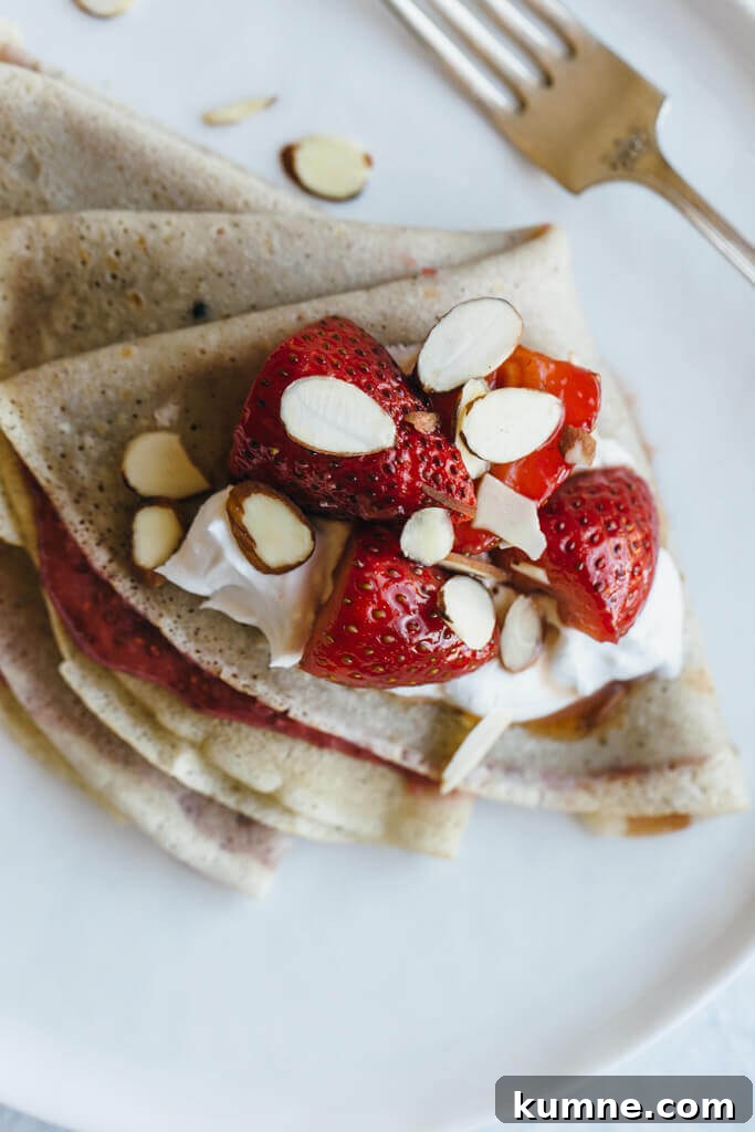 (gluten-free, paleo) Vanilla bean cassava flour crepes with strawberry chia jam. Sweet breakfast crepes are filled with homemade strawberry chia jam and topped with coconut whipped cream and almonds.