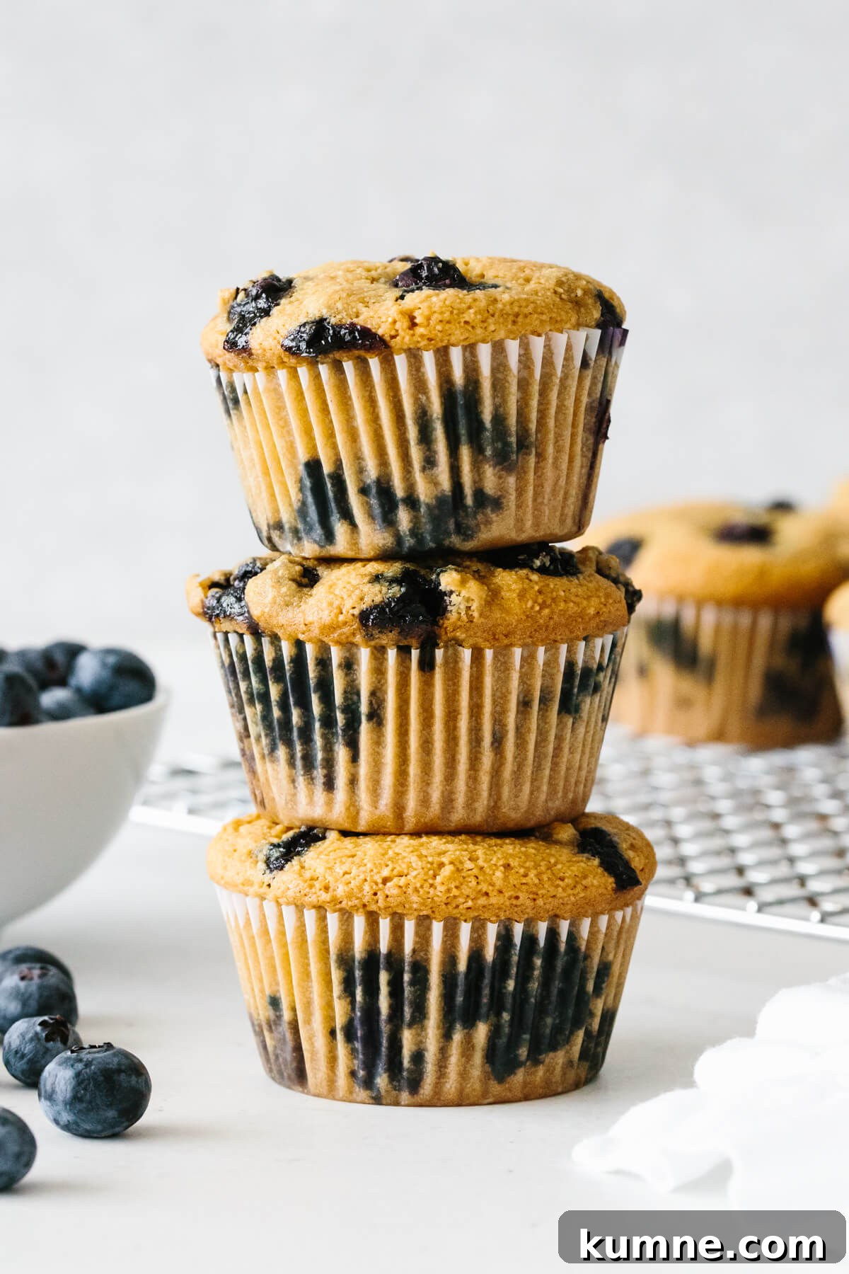 Three paleo blueberry muffins stacked on top of each other.