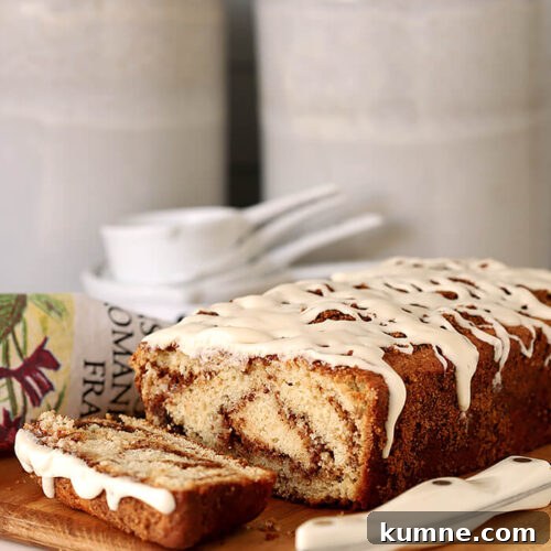 Cinnamon Roll Quick Bread with Cream Cheese Glaze Served on a Bread Board with Slices