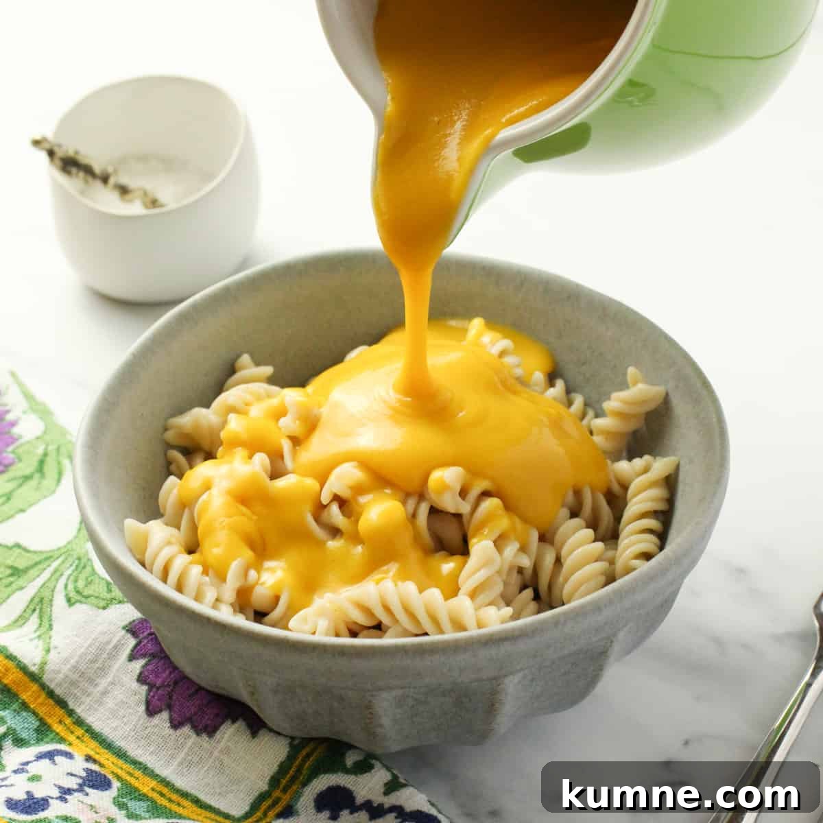 a pale blue bowl of pasta with vegan cheese sauce