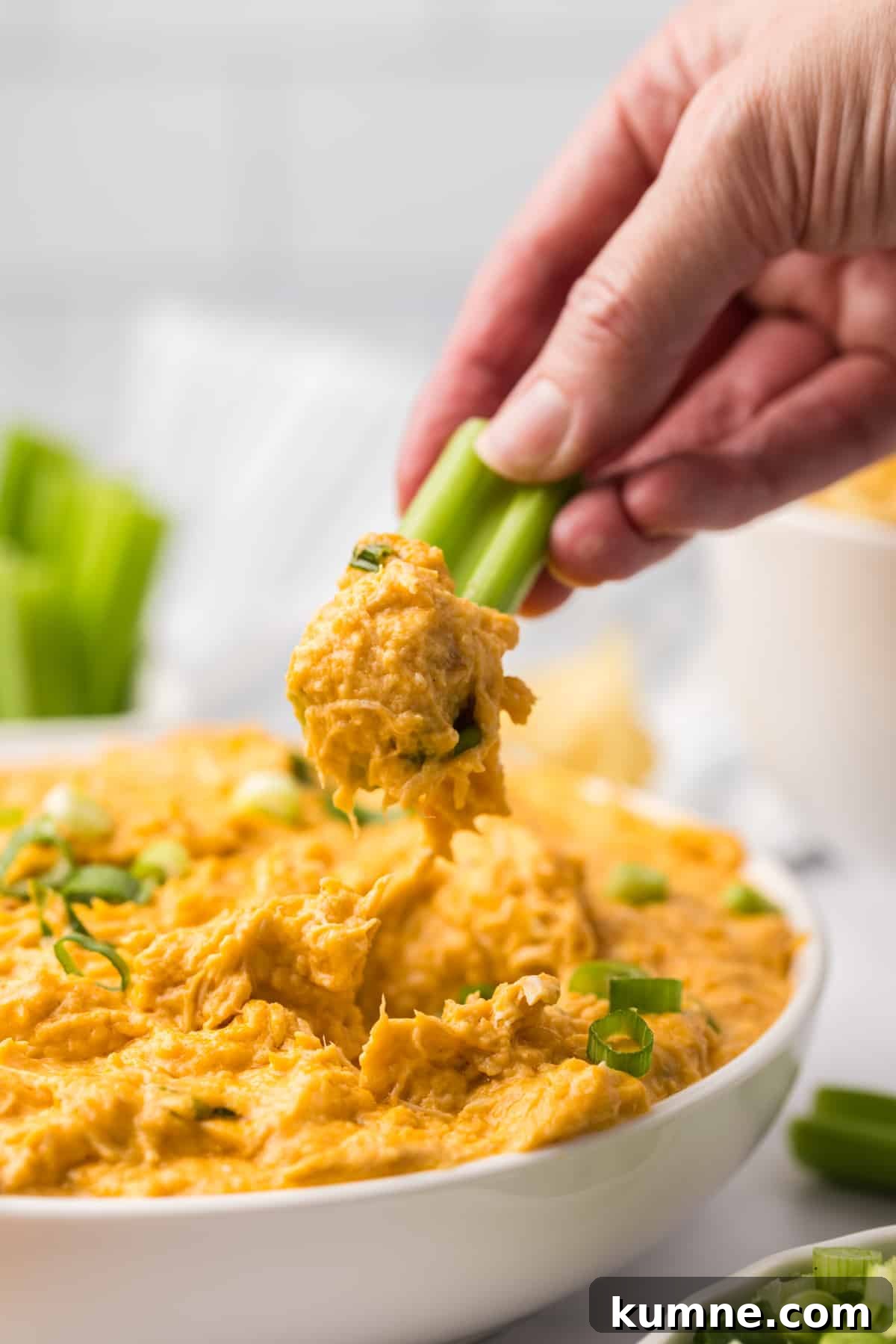 Slow Cooker Buffalo Chicken Dip Recipe for Game Day Snacks 15 Dipping a celery stick into a bowl of buffalo chicken dip.