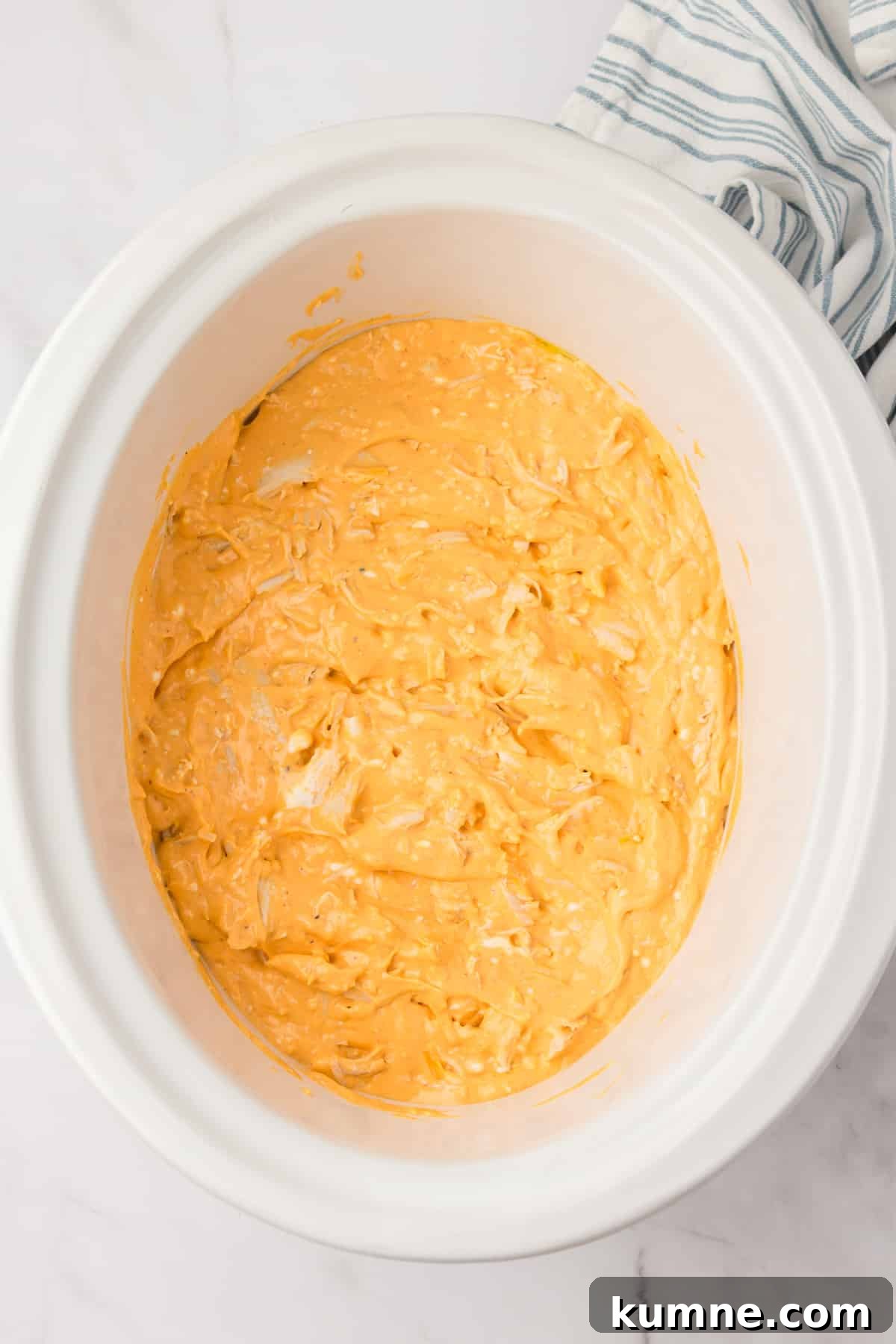 Slow Cooker Buffalo Chicken Dip Recipe for Game Day Snacks 8 A white crock pot filled with a cheesy chicken dip.