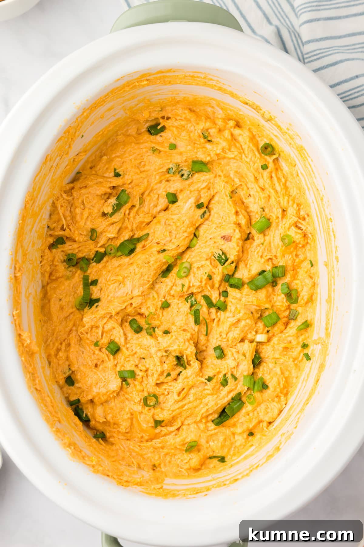Slow Cooker Buffalo Chicken Dip Recipe for Game Day Snacks 10 A white crock pot with a cheesy chicken dip inside.