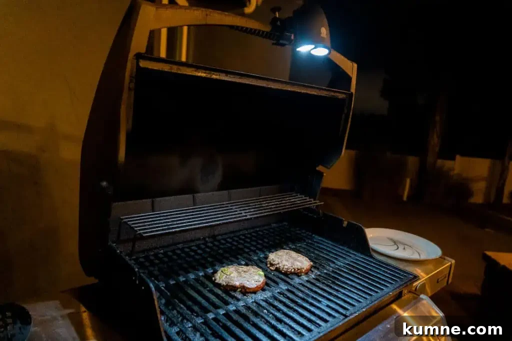 Cave Tools Grill Light Review: Is It Worth Buying? 4 Cave Tools Barbecue Grill Light attached on a grill and being used at night to cook hamburger patties