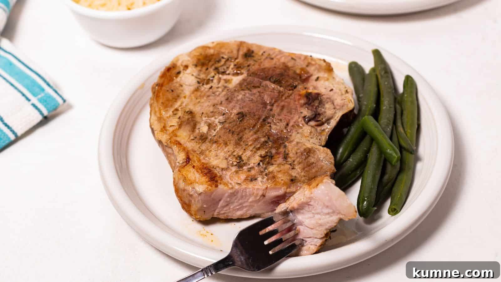 Oven baked pork steak on a plate with green beans and a fork on the side.