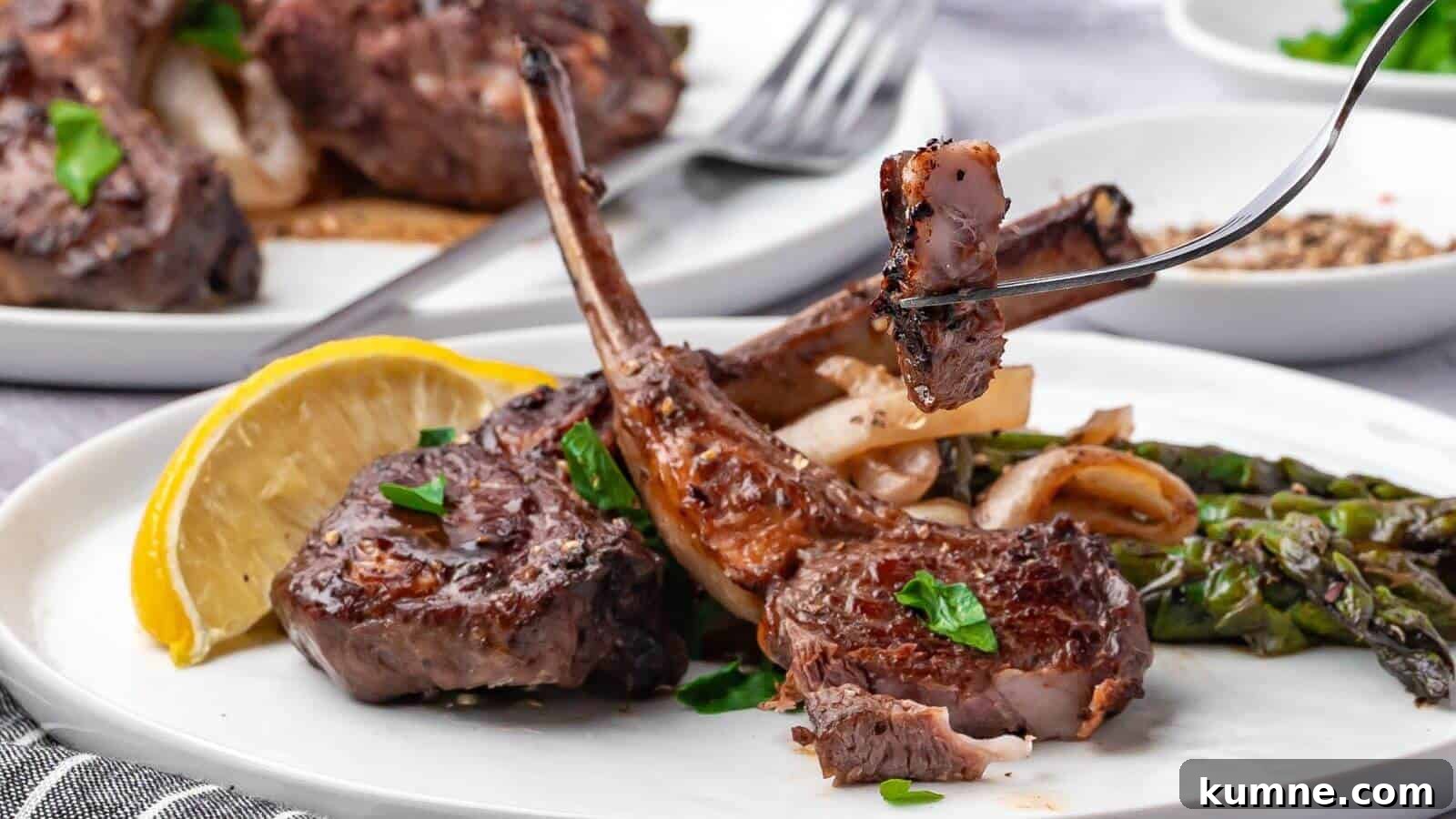 Plate of grilled lamb chops with asparagus, onions, parsley garnish, and a lemon wedge. A fork holds a piece of lamb.