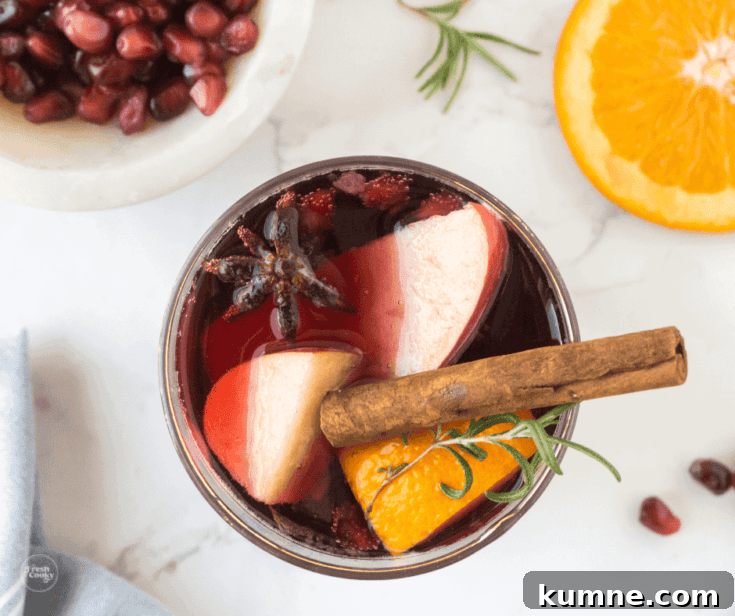 A glass of spiced pomegranate sangria garnished with cinnamon.