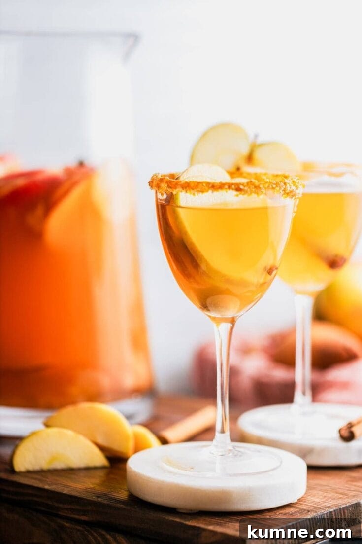 A couple glasses of caramel apple sangria garnished with apple slices.