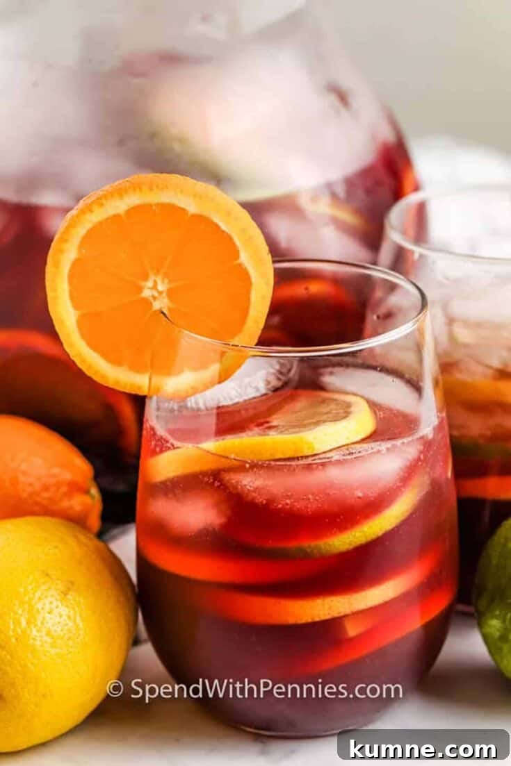 A glass of red wine sangria garnished with orange slices.