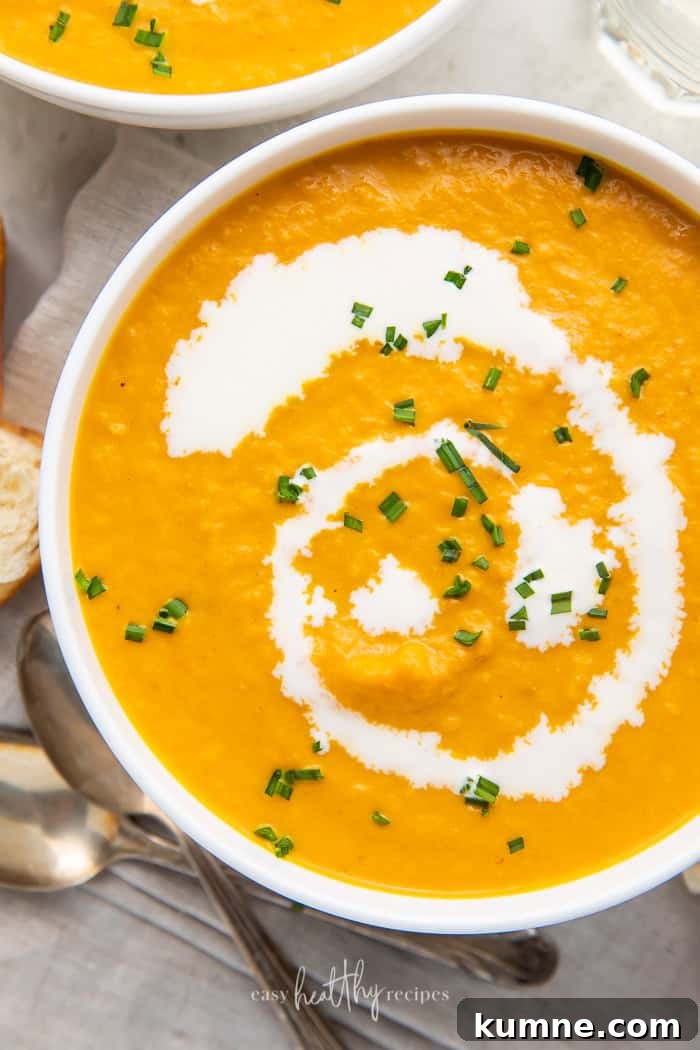 Creamy Pumpkin Bisque Recipe — Smooth Autumn Soup 3 Close-up shot of pumpkin bisque in white bowls garnished with chives and cream