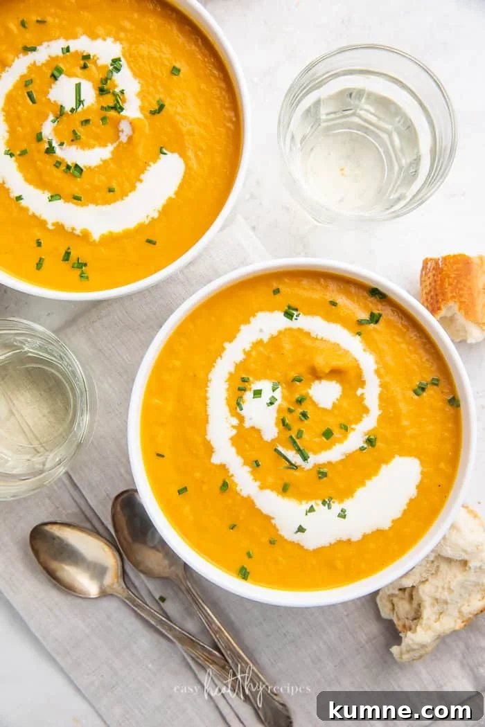 Creamy Pumpkin Bisque Recipe — Smooth Autumn Soup 4 Two bowls of pumpkin bisque surrounded by spoons, glasses, and bread