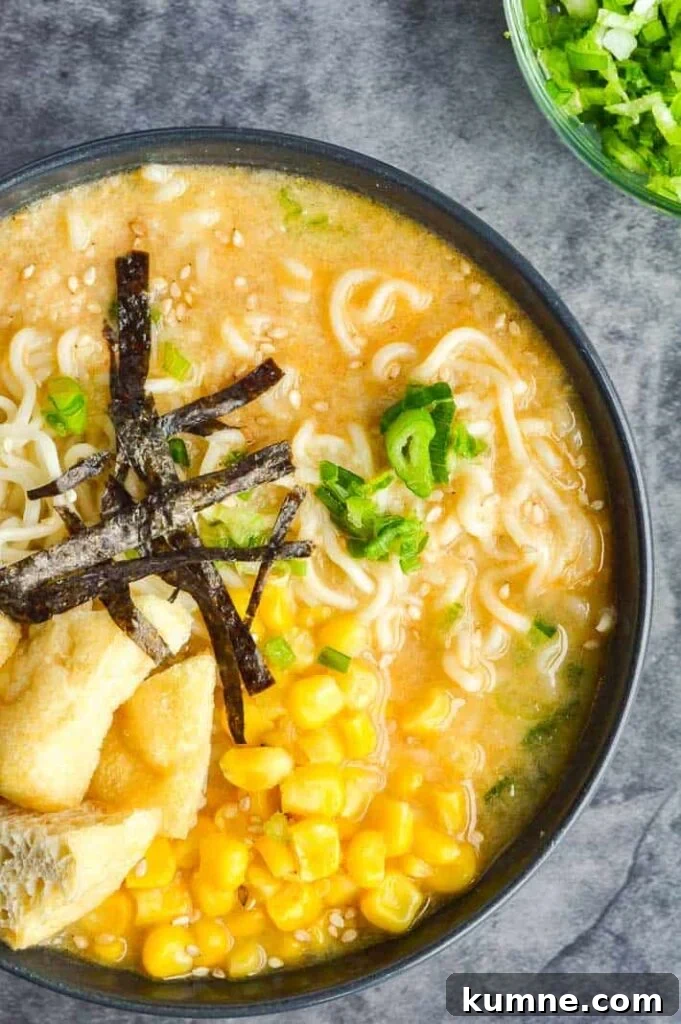 Quick 15-Minute Vegan Miso Ramen Recipe 3 Top down view of bowl of ramen on grey background with sliced green onions in the corner
