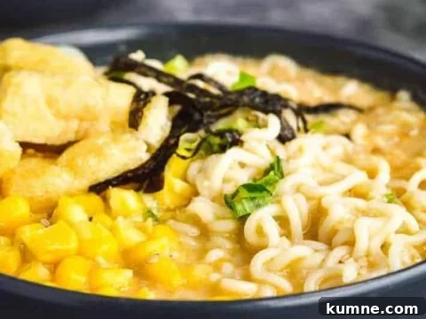 Side view of two gray bowls full of creamy broth, ramen noodles, spring onions, tofu and sweetcorn