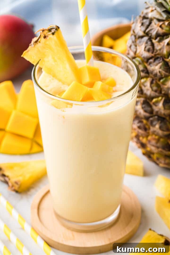 Creamy Mango Pineapple Smoothie Recipe for Tropical Refreshment 2 Mango Pineapple Smoothie in glass on wooden coaster.