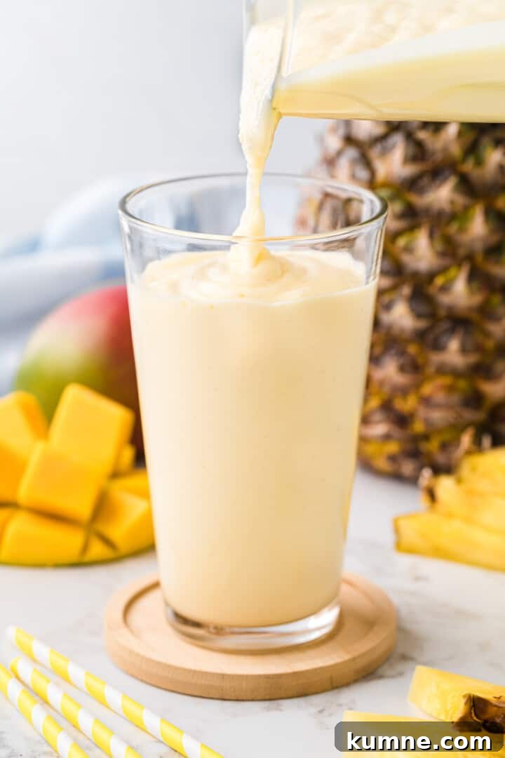 Creamy Mango Pineapple Smoothie Recipe for Tropical Refreshment 7 pouring the smoothie from the blender into a glass.