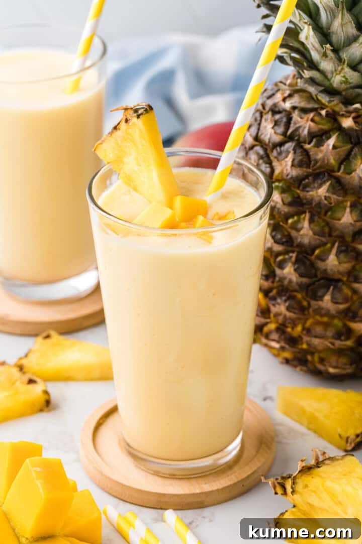 Creamy Mango Pineapple Smoothie Recipe for Tropical Refreshment 10 Mago Pineapple Smoothie garnished with fresh mangoes and a pineapple slice.