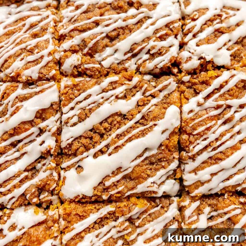 Close-up of crumbly baked bars cut into squares, topped with white icing drizzles.