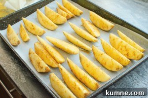 Potato wedges on a baking tray lined with white parchment paper