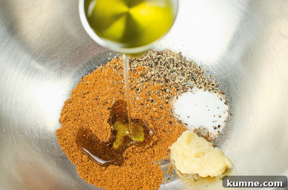 Garam masala, pepper, salt, garlic puree and olive oil in a silver mixing bowl